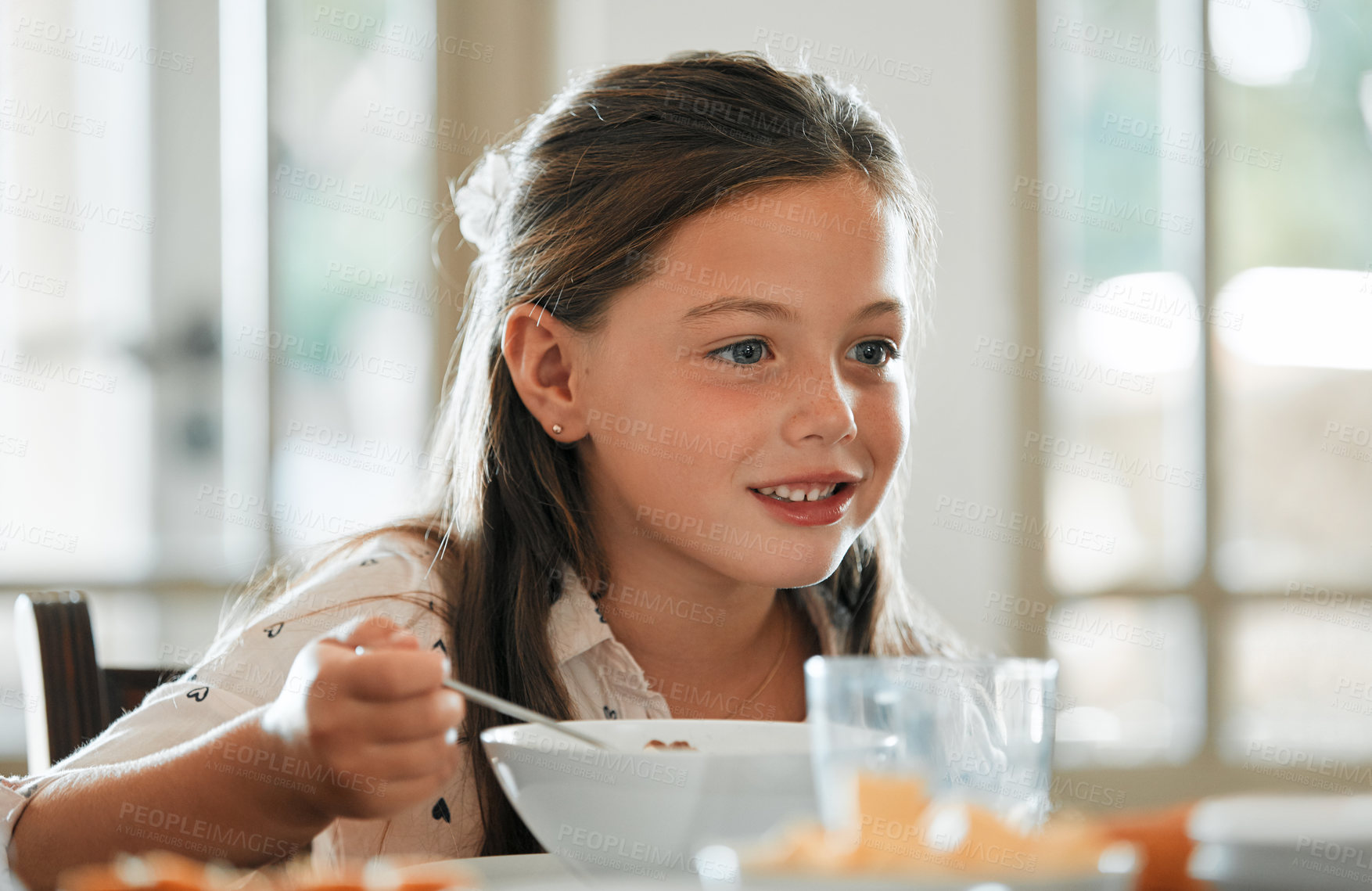 Buy stock photo Happy, kid and eating breakfast in home with bowl, healthy food and nutrition for child development. Hungry, girl smile and morning meal in dining room with spoon, growth and vitamins for wellness.