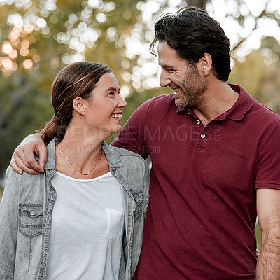 Buy stock photo Cropped shot of an affectionate couple taking a walk through the park