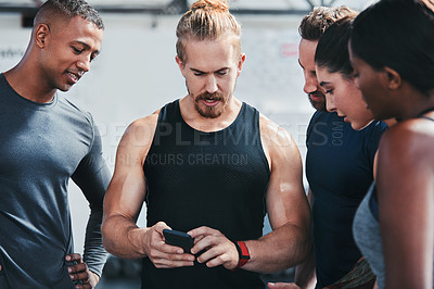Buy stock photo Cropped shot of a group of young athletes looking at a cellphone while standing in the gym