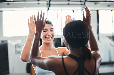 Buy stock photo Cropped shot of two attractive young female athletes high-fiving during a workout in the gym