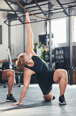 Buy stock photo Full length shot of a handsome young male athlete going through his warmup routine in the gym