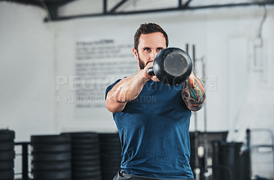 Buy stock photo Cropped shot of a handsome young male athlete working out with a kettle bell in the gym