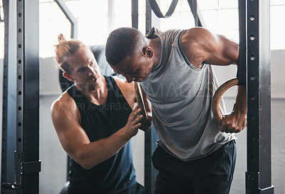 Buy stock photo Shot of a man working out with the help of his coach at the gym