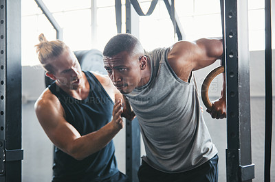 Buy stock photo Shot of a man working out with the help of his coach at the gym