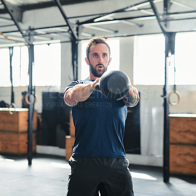 Buy stock photo Cropped shot of a handsome young male athlete working out with a kettle bell in the gym