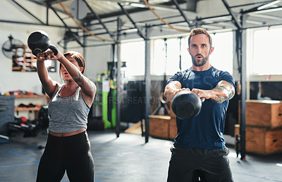 Buy stock photo Shot of two people working out using kettle bells  at the gym
