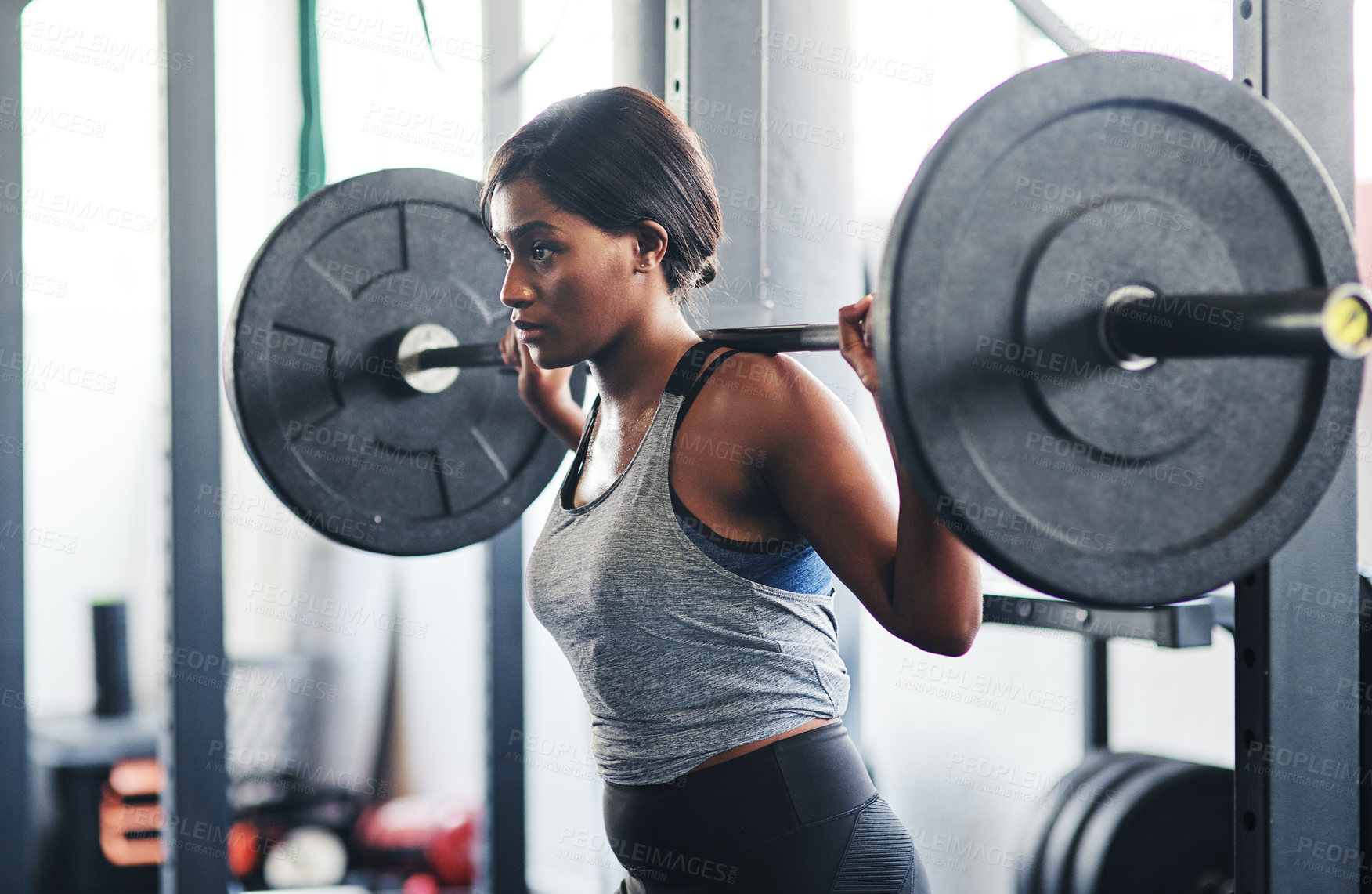 Buy stock photo Fitness, woman and exercise with barbell in gym for muscle conditioning, power or strength benefits. Squat rack, bodybuilder and African person with weights, resistance training and workout lifestyle