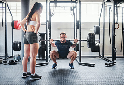 Buy stock photo Shot of a man working out with the help of his coach at the gym
