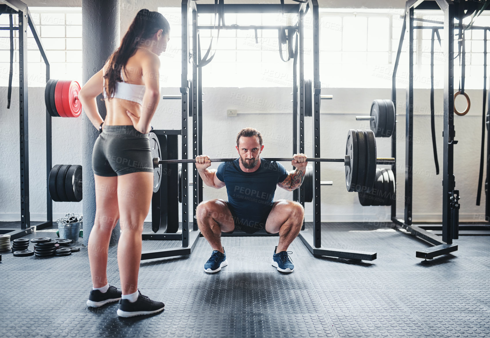 Buy stock photo Shot of a man working out with the help of his coach at the gym