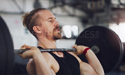 Buy stock photo Shot of a young man exercising with a barbell in a gym