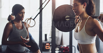 Buy stock photo Shot of a woman exercising with a barbell with the help of a trainer in a gym