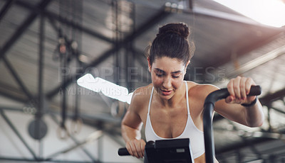 Buy stock photo Shot of a young woman working out on an exercise bike in a gym