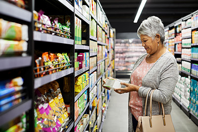 Buy stock photo Shot of a mature woman shopping for groceries in a supermarket