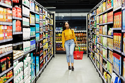 Buy stock photo Shot of a young woman shopping for groceries in a supermarket