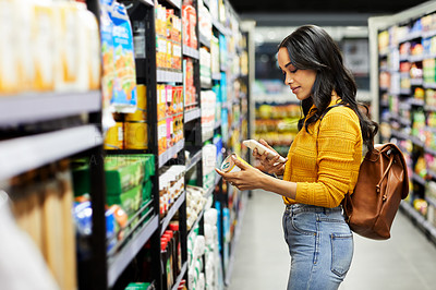 Buy stock photo Shot of a young woman shopping for groceries in a supermarket
