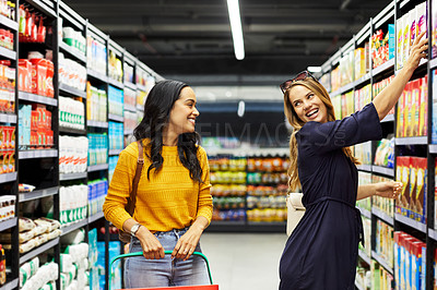 Buy stock photo Shot of two young woman shopping for groceries in a super market