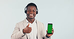 Green screen, call center and black man with thumbs up on cellphone in studio for crm, contact us or enquiry. Happy, portrait and technical support agent with phone and headset on white background.