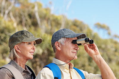 Buy stock photo A cropped shot of a senior man looking through a binocular while standing next to his wife