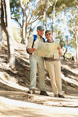 Buy stock photo Shot of a senior couple using a map while standing in a forest
