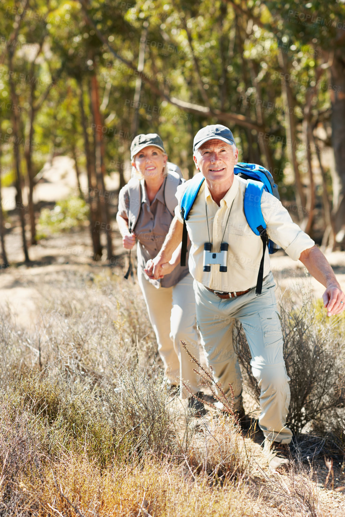 Buy stock photo Holding hands, hiking and smile with old couple in nature for bonding, adventure or journey. Anniversary date, trekking and fitness with senior man and woman outdoor for tourism, wellness and explore