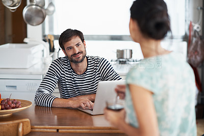 Buy stock photo Shot of a handsome young man sitting with his laptop and looking lovingly at his wife
