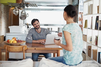 Buy stock photo Shot of a handsome young man sitting with his laptop and looking lovingly at his wife