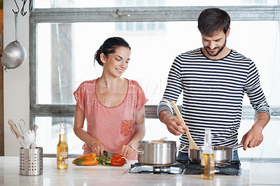 Buy stock photo Shot of a loving young couple cooking together in the kitchen