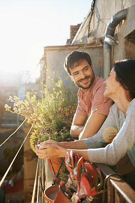 Buy stock photo Shot of a beautiful young couple standing next to each other on a balcony overlooking an urban setting