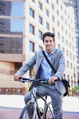 Buy stock photo A handsome businessman riding his bicycle to work in the city central