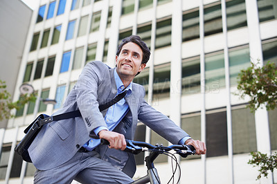 Buy stock photo A handsome businessman riding his bicycle to work in the city central