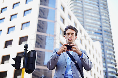 Buy stock photo A handsome businessman using his smartphone to get direction in the city central