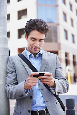 Buy stock photo A handsome businessman using his mobile in the city central