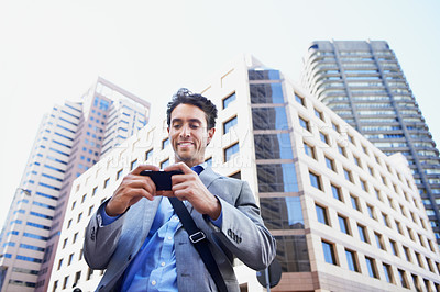 Buy stock photo A handsome businessman using his smartphone to get direction in the city central