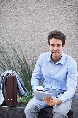 Buy stock photo A handsome businessman using his tablet while sitting out in the city central and having a break