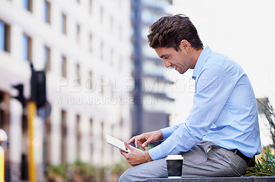 Buy stock photo A handsome businessman using his tablet while sitting out in the city central and having a break