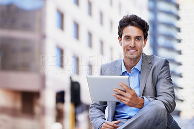 Buy stock photo A handsome businessman using his tablet while sitting out in the city central and having a break
