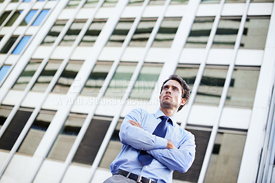 Buy stock photo A determined businessman standing in the city central with his arms folded