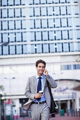 Buy stock photo A handsome businessman on his cellphone while holding a cup of coffee in the city central