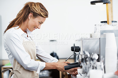 Buy stock photo A pretty barista using the coffee machine