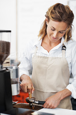 Buy stock photo Portrait of a pretty barista using the coffee machine and making coffee