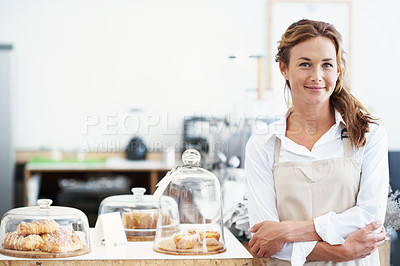 Buy stock photo Portrait of a pretty baker standing in front of ready to serve pastries