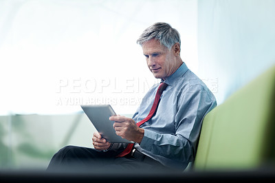 Buy stock photo Shot of a senior businessman using his tablet indoors