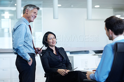 Buy stock photo Shot of three businesspeople discussing something at a workstation