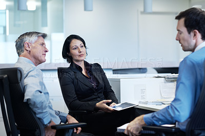 Buy stock photo Shot of three businesspeople discussing something at a workstation