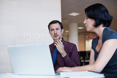 Buy stock photo Shot of two businesspeople having a discussion while using a laptop