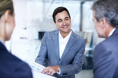 Buy stock photo Over the shoulder shot of a group of businesspeople discussing documents in an office