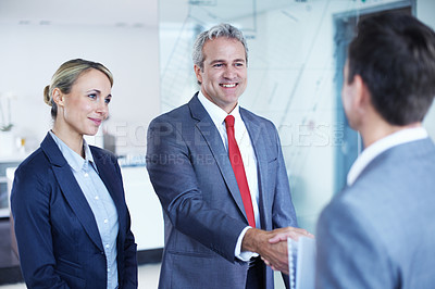 Buy stock photo Shot of two businesspeople shaking hands while having a standing in an office