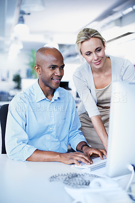Buy stock photo Shot of two office workers talking over a desktop computer in an office