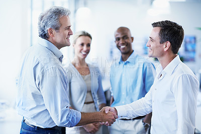 Buy stock photo Shot of a diverse group of coworkers shaking hands and talking in an office