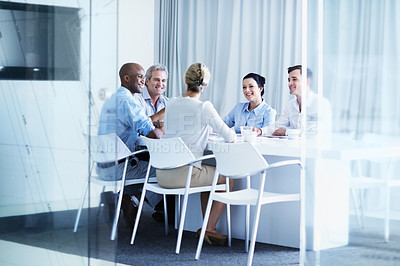 Buy stock photo Through the window shot of a group of businesspeople having a meeting in a boardroom